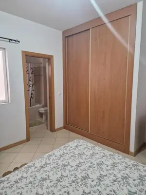 a bedroom with a sliding door with a bathroom at Condomínio palma azul II in Praia