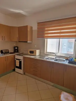 a kitchen with wooden cabinets and a sink and a window at Condomínio palma azul II in Praia