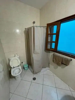 a bathroom with a toilet and a shower and a window at Casa Cor de Rosa in Praia