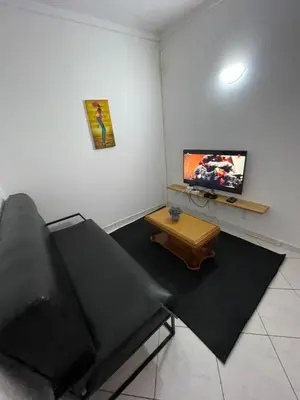 a living room with a black couch and a flat screen tv at Casa Cor de Rosa in Praia