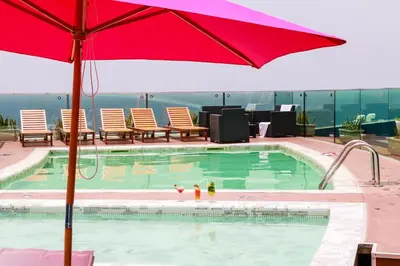 a large pool with a red umbrella and chairs at Hotel Vip Praia in Praia