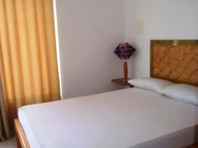 a bedroom with a white bed with a yellow curtain at Zena Star in Tarrafal