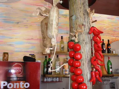 a bar with a bunch of wine bottles and red peppers at Zena Star in Tarrafal