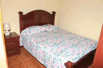 a bedroom with a bed with a floral bedspread and a night stand at Ramos Apartamento in São Filipe