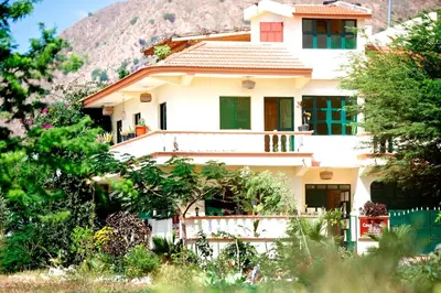 a white house with a mountain in the background at Casa Strela B&B Tarrafal in Tarrafal