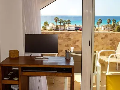 a computer monitor on a desk with a view of the beach at Calma de Sal Santana Ocean View Apartment in Santa Maria