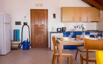 a kitchen with a table and chairs and a refrigerator at Calma de Sal Santana Ocean View Apartment in Santa Maria
