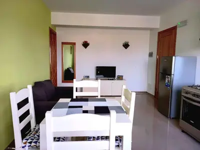 a living room with a table and a refrigerator at Apartamento em Santa Maria- Espaçoso&Confortável in Santa Maria