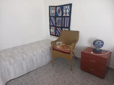 a bedroom with a bed and a chair and a dresser at Casa Herminia in Tarrafal