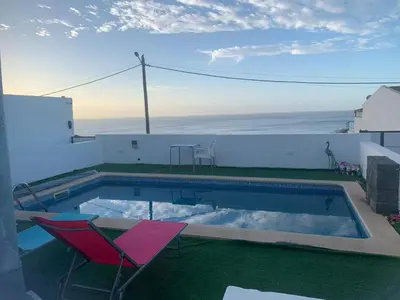 a swimming pool with a red chair and a table and a chair at Palmira House in Cidade Velha