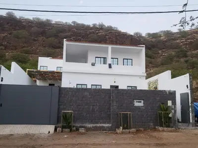 a white house with a black wall at Palmira House in Cidade Velha