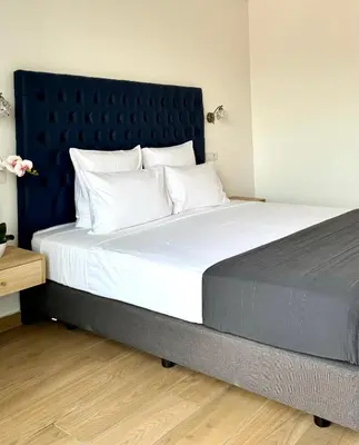 a large bed with a blue headboard and white pillows at Hôtel Blue Sky in Tarrafal