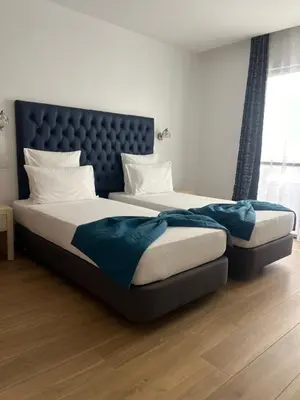 two beds in a bedroom with a blue headboard at Hôtel Blue Sky in Tarrafal