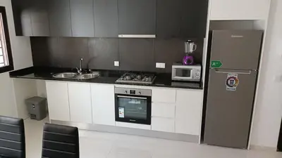 a kitchen with a stove and a refrigerator at T2 da Marília fonte francês in Mindelo