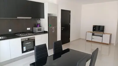 a kitchen with a table and a stove and a microwave at T2 da Marília fonte francês in Mindelo