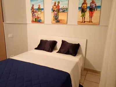 a bedroom with a bed and paintings on the wall at Apartamento Djadsal Moradias L01 próximo à praia in Santa Maria