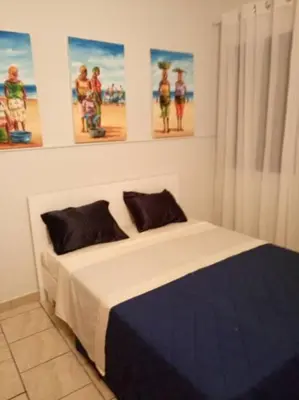 a bed in a bedroom with pictures on the wall at Apartamento Djadsal Moradias L01 próximo à praia in Santa Maria