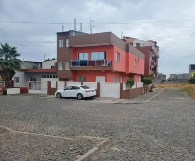 a car parked in front of a red building at Jbct & SOLANGE APART in Praia