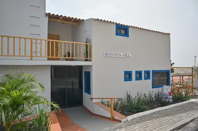 a white house with blue windows and a balcony at Encosta Azul in Cidade Velha