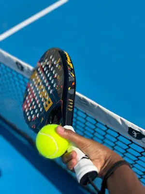 a person holding a tennis racket and a tennis ball at Encosta Azul in Cidade Velha