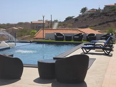 a swimming pool with lounge chairs and a fountain at Encosta Azul in Cidade Velha