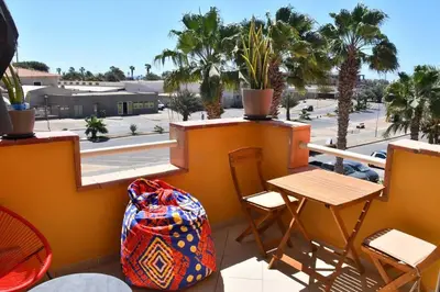 a balcony with a table and chairs and palm trees at Kyaala Djadsal Moradias pool&sea in Santa Maria
