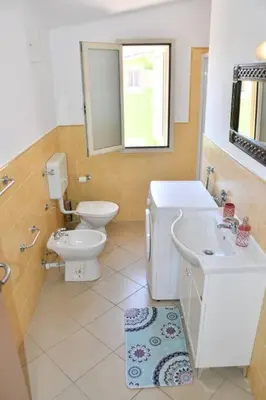 a bathroom with a toilet and a sink and a mirror at Kyaala Djadsal Moradias pool&sea in Santa Maria