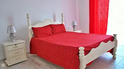 a bedroom with a bed with a red blanket and two lamps at TARRAFAL SN TOUR in Tarrafal