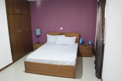 a bedroom with a bed and a purple wall at T1 conforto in Praia