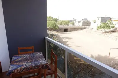 a table and chairs on a balcony with a view of a street at Residencial Ribeira Torta in Porto Novo