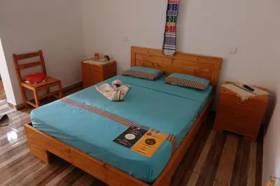 a bedroom with a large wooden bed with a blue mattress at Residencial Ribeira Torta in Porto Novo