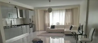 a living room with a white couch and a kitchen at Hotel Xinte na casa in Tarrafal