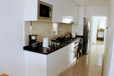 a kitchen with white cabinets and a black counter top at ACG Plato Vacation Apartment with Balcony in Praia