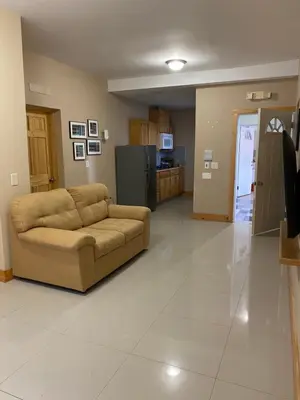a living room with a couch and a kitchen at Spencer Residencial QUARTOS in Praia