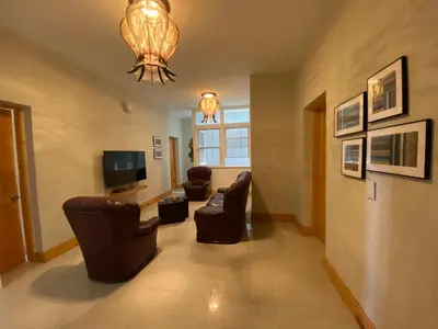 a living room with couches and a television and a chandelier at Spencer Residencial QUARTOS in Praia