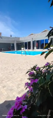 a woman standing next to a swimming pool with purple flowers at Residência Águia in Praia