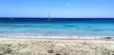 a person swimming in the ocean with a boat in the water at Residencial Ilha do Maio App 101 in Santa Maria