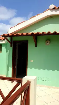 a green house with a door and a balcony at Residencial Ilha do Fogo app 205 in Santa Maria