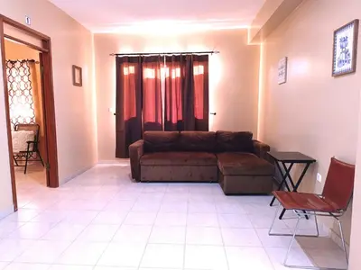 a living room with a brown couch and a window at Pensão Dona Fica in Tarrafal
