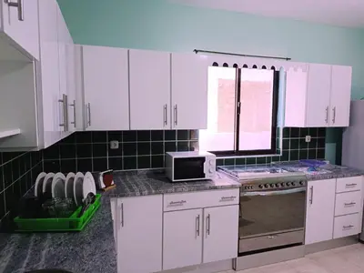 a kitchen with white cabinets and a microwave at Pensão Dona Fica in Tarrafal