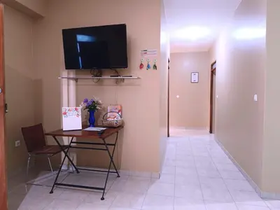 a hallway with a table and a television on a wall at Pensão Dona Fica in Tarrafal