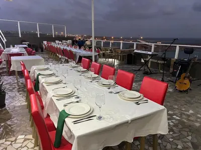 a long table with white tables and red chairs at Djeu View in Praia