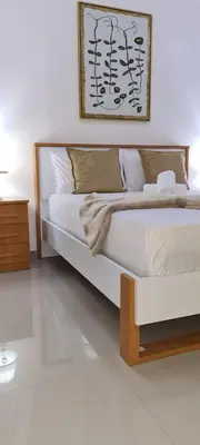 a bedroom with a white bed with a wooden frame at Zeyden Place Apt in Praia