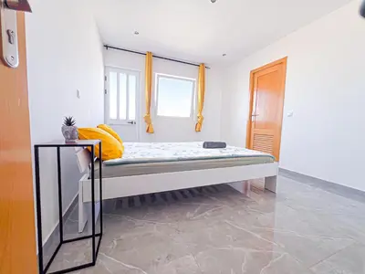 a bed in a room with two windows at Brand new apartment in Mindelo in Mindelo