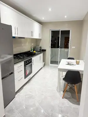 a kitchen with white cabinets and a white table at Brand new apartment in Mindelo in Mindelo
