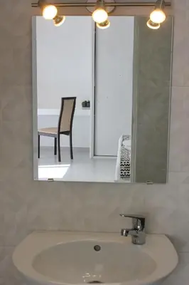 a bathroom sink with a mirror and a chair at KANDAKE APARTMENT Sal Rei Wi-Fi in Sal Rei