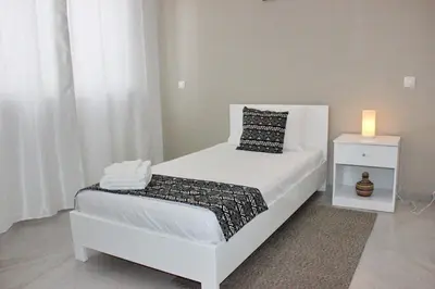 a bedroom with a white bed and a candle on a night stand at KANDAKE APARTMENT Sal Rei Wi-Fi in Sal Rei