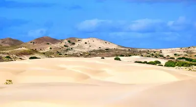 a group of sand dunes with mountains in the background at KANDAKE APARTMENT Sal Rei Wi-Fi in Sal Rei