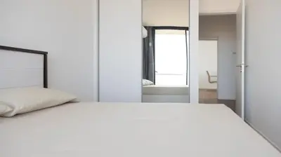 a bedroom with a large white bed and a mirror at Lux 3-BR: Panoramic Sea View & Rooftop Pool in Praia