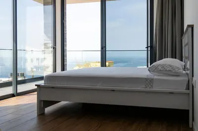a bed in a room with a large window at Lux 3-BR: Panoramic Sea View & Rooftop Pool in Praia